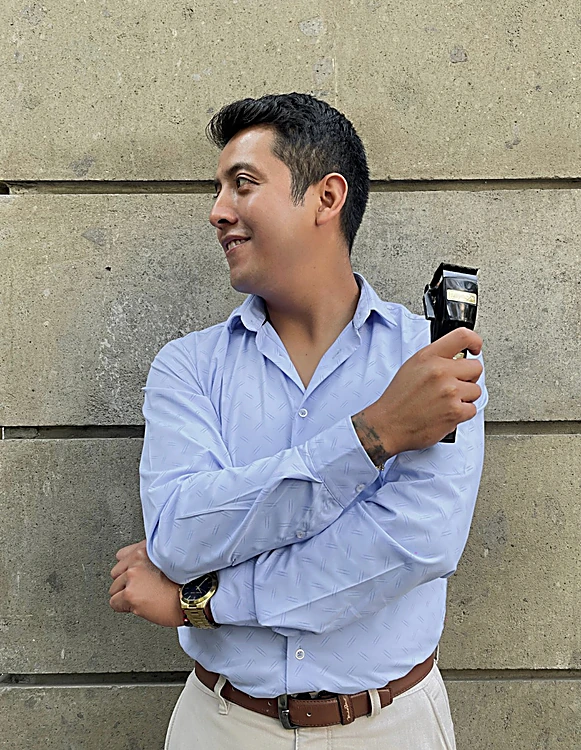 Dan, fundador de DanStudio, con camisa azul y máquina de corte frente a un muro de piedra